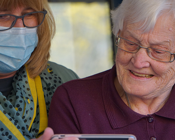 2 ladies looking at a phone and smiling