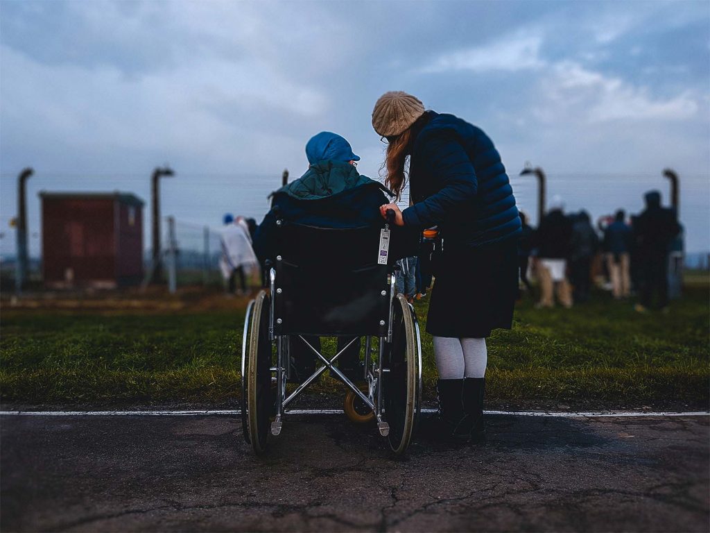 2 people outside. 1 is in a wheelchair